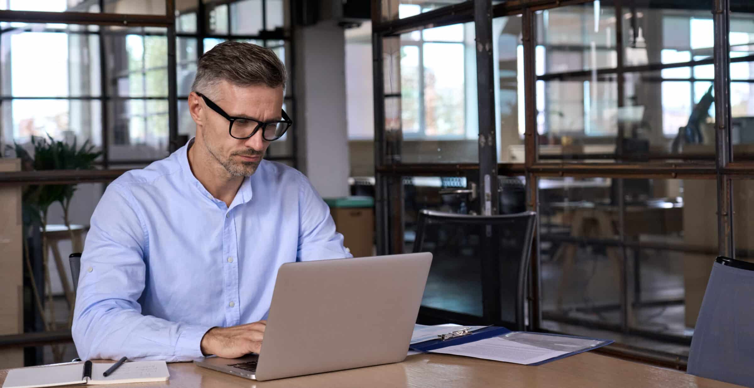 Busy mature business man lawyer ceo using laptop computer working in office.